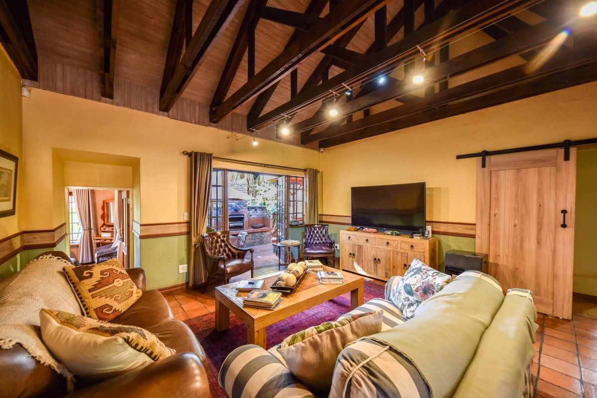 Spacious living room featuring a vaulted ceiling with exposed timber trusses, terracotta flooring, and direct access to an outdoor patio area.