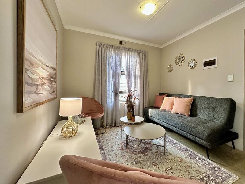 A cozy living room featuring neutral wall tones, ceiling cornicing, and a functional layout suitable for relaxation.