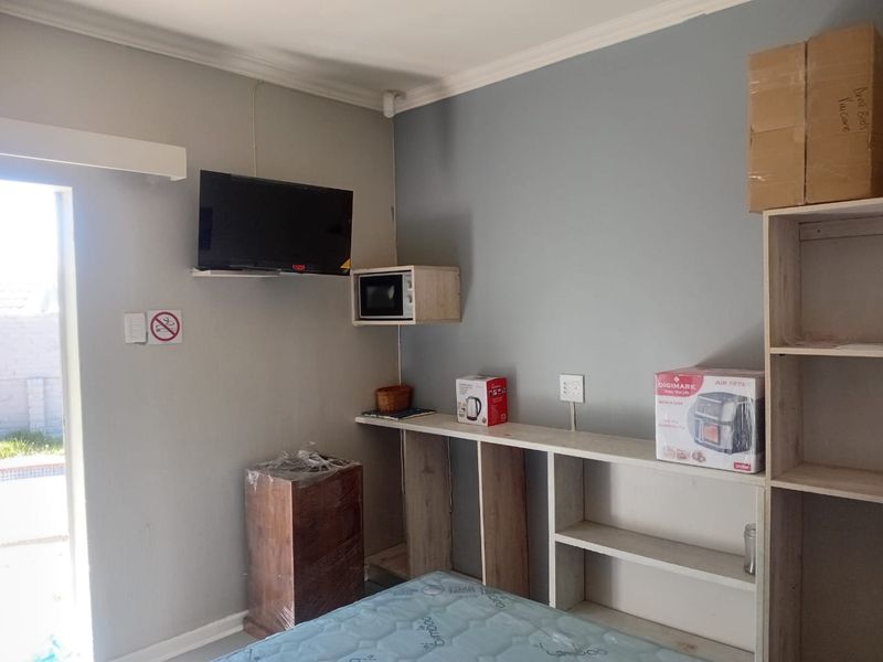 A bedroom featuring built-in shelving units, a wall-mounted microwave shelf, and direct access to an outdoor area.