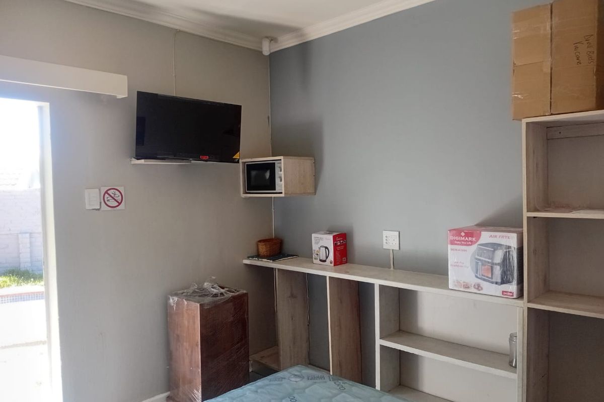 A bedroom featuring built-in shelving units, a wall-mounted microwave shelf, and direct access to an outdoor area.