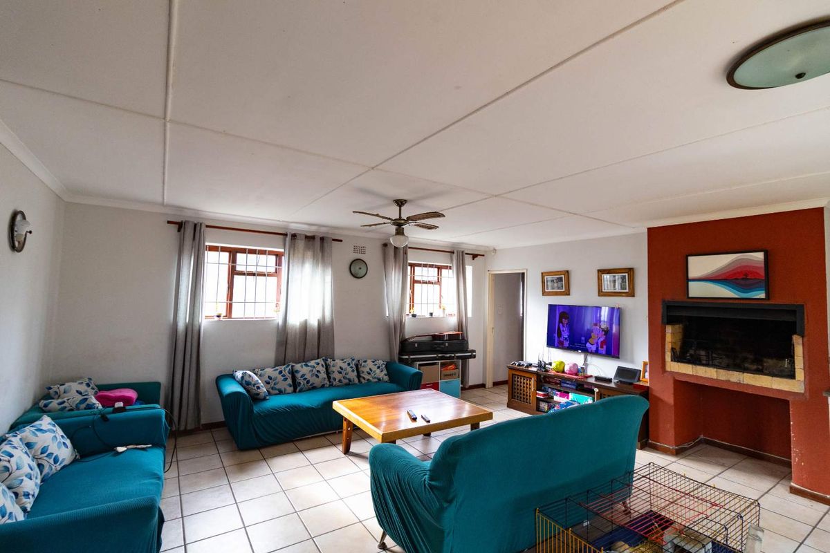 Spacious living room featuring tiled flooring, a built-in fireplace, and a ceiling fan, offering a comfortable and functional family space.