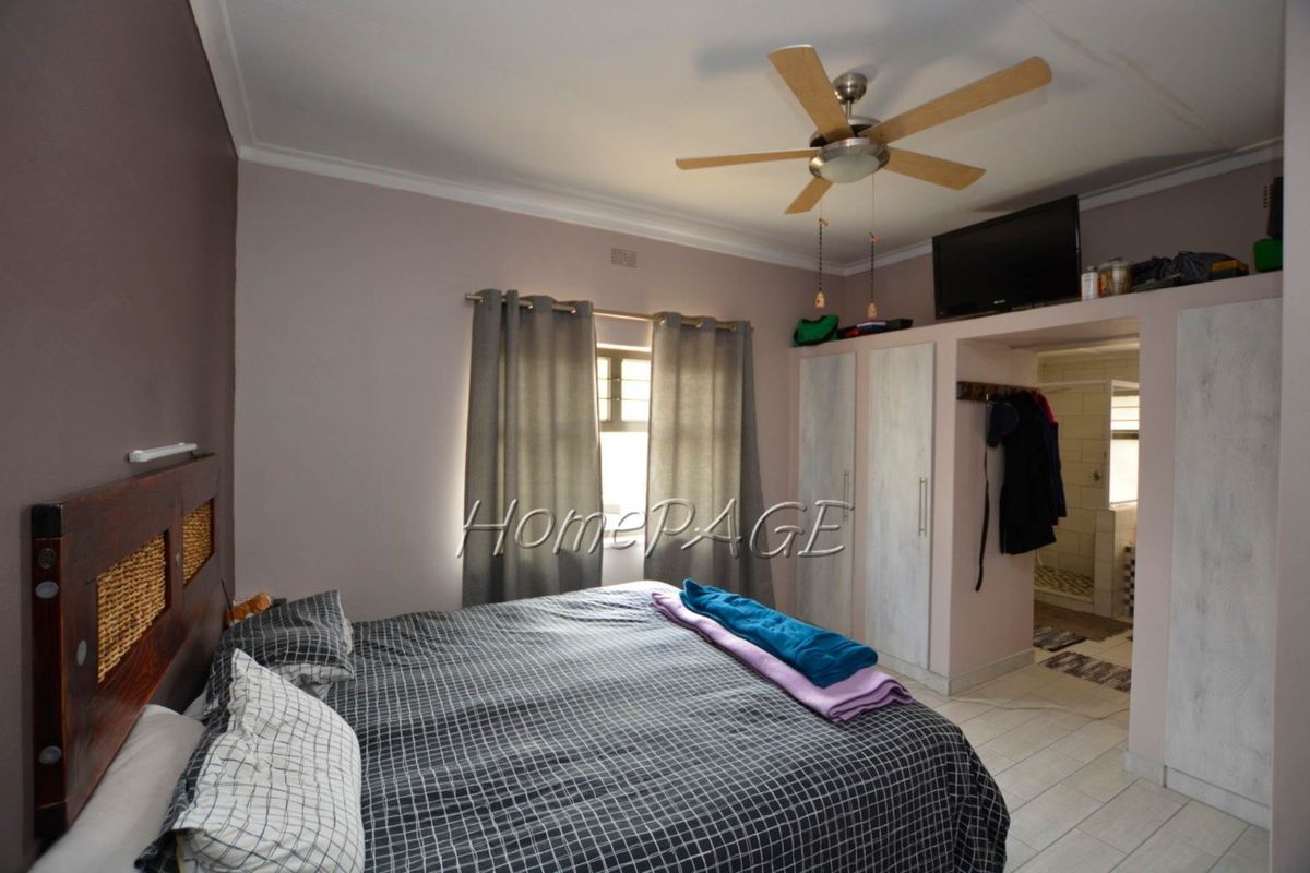A bedroom featuring built-in cupboards, a ceiling fan, and an en-suite bathroom access point.