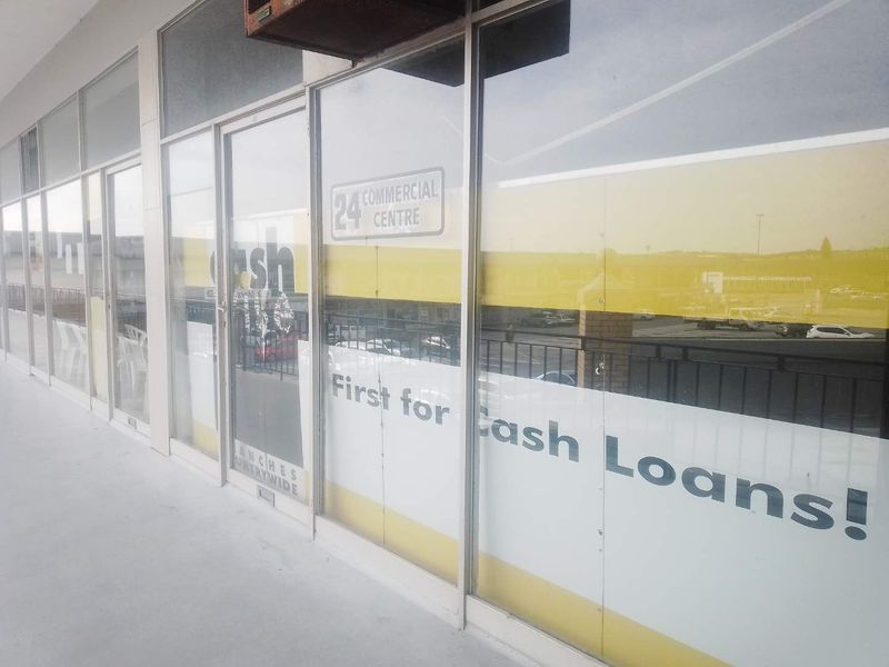 Exterior view of a commercial shopfront featuring large glass windows and an entrance door, located within a commercial centre.