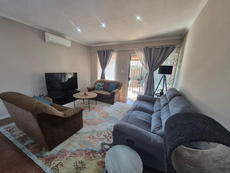 A comfortable living room featuring a split-system air conditioner, recessed lighting, and direct access to an outdoor area through a sliding glass door.