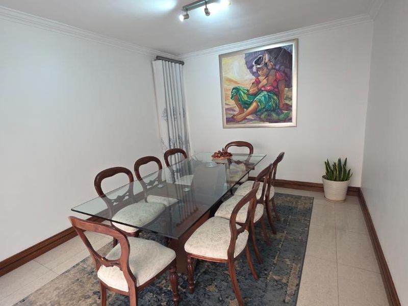A well-maintained dining room featuring neutral tiled flooring, cove cornicing, and modern track lighting, providing a clean and functional space for formal dining.