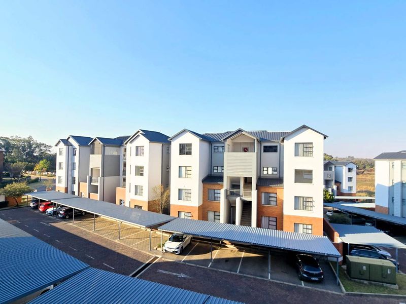 An elevated view of a modern apartment complex featuring multi-story residential buildings with brick and plaster facades and dedicated covered parking bays.