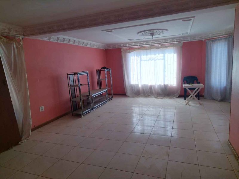 Spacious living area featuring tiled flooring and decorative ceiling molding, offering a blank canvas for renovation and interior design updates.