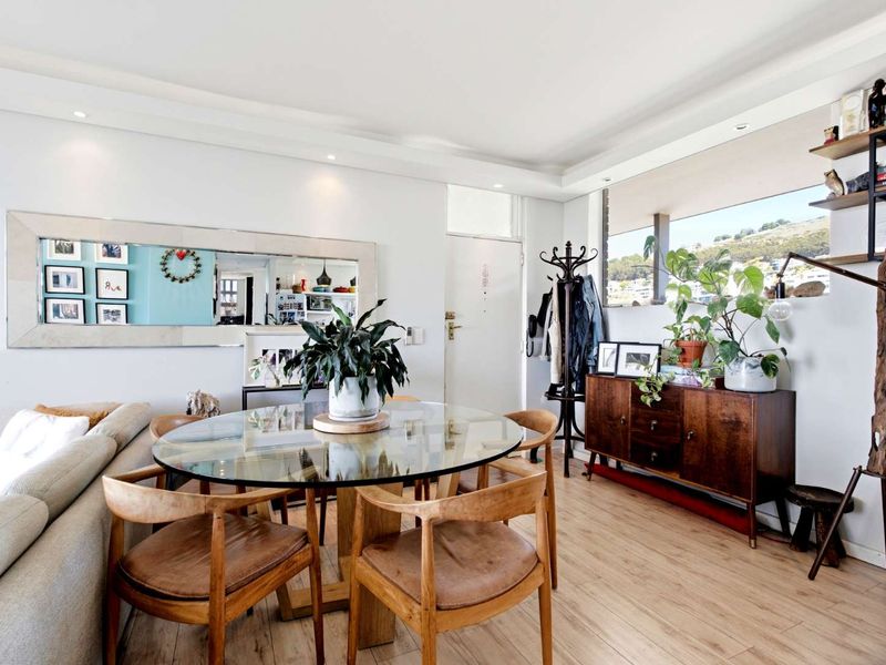 A bright and well-maintained living area featuring laminate flooring, recessed downlighting, and elegant cove ceiling moulding, creating a comfortable and inviting space.