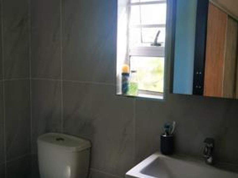 A functional bathroom featuring modern grey wall tiles, a vanity basin with mixer tap, and a built-in medicine cabinet.