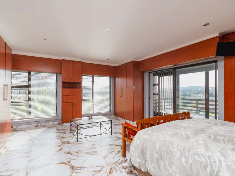 Spacious bedroom featuring extensive built-in wooden cabinetry, marble-look tiled flooring, and large sliding doors providing access to an outdoor balcony area.