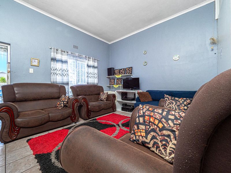 A living room featuring tiled flooring, a sliding glass door with security gate, and cove cornicing, providing a functional and accessible living space.