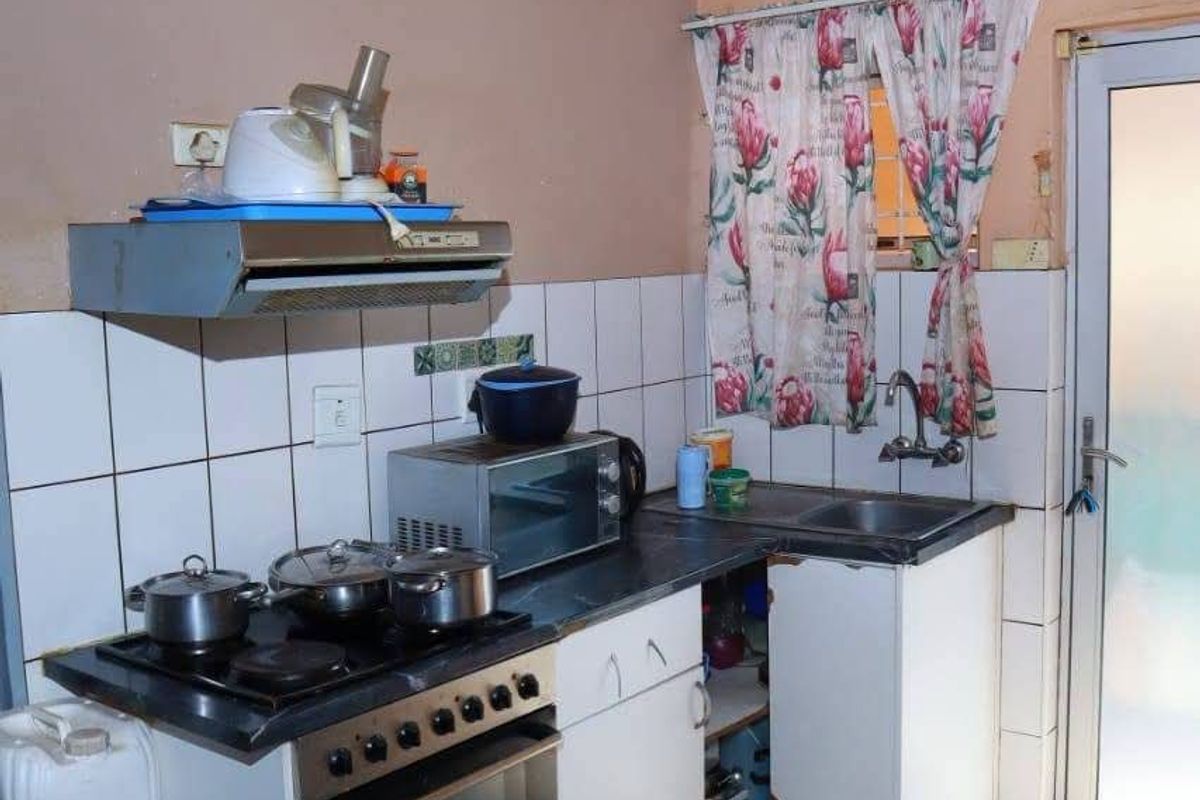 Compact kitchen featuring a built-in oven, hob, extractor fan, and tiled splashback, with direct access to an exterior door.