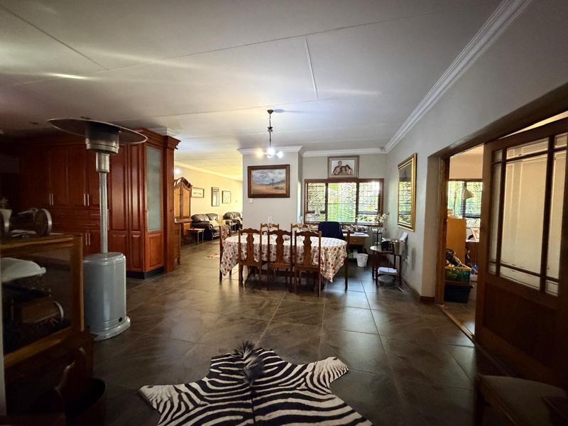 Spacious open-plan living and dining area featuring large format floor tiles, crown molding, and integrated wooden cabinetry.