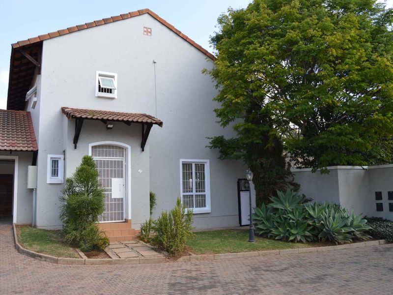 Front elevation of a residential house featuring a paved driveway, tiled roof, and secure entrance with security gate and bars.