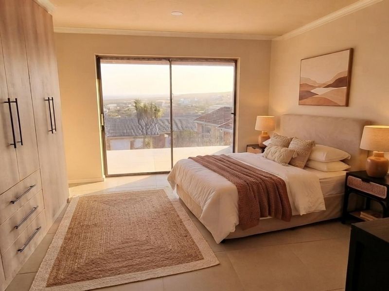 A well-maintained bedroom featuring extensive built-in cabinetry, neutral tiled flooring, and a large sliding glass door providing natural light and access to the exterior.