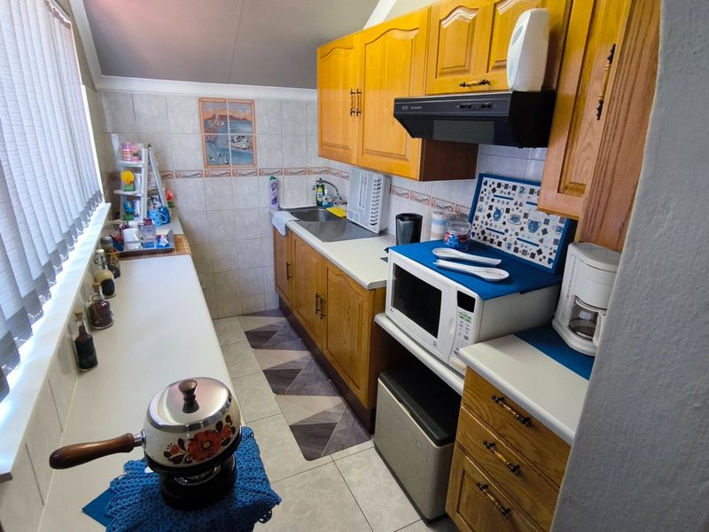 A functional galley-style kitchen featuring wooden cabinetry, tiled backsplash, and ample counter space, offering a practical layout for daily meal preparation.