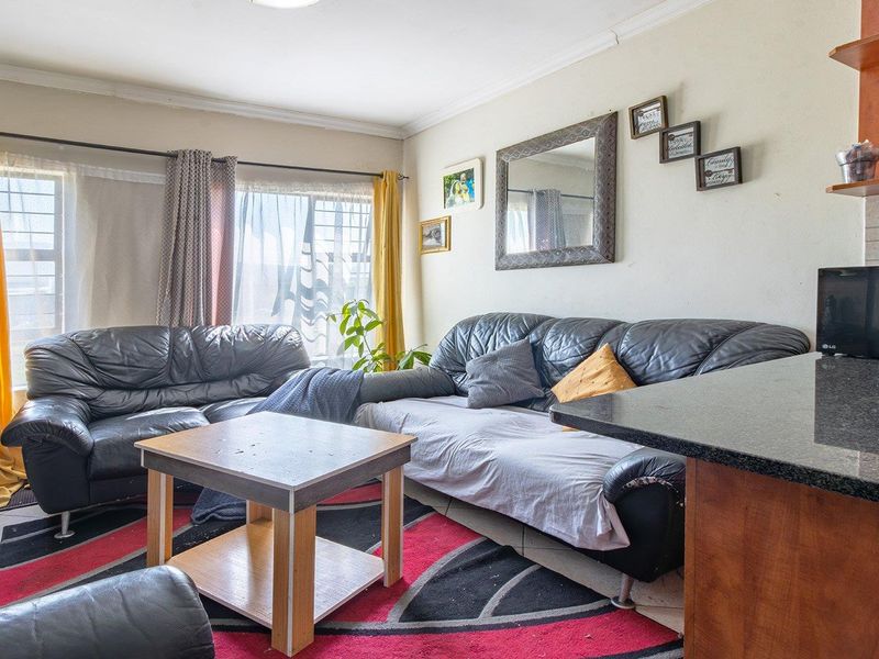 Open plan living area featuring tiled flooring and a kitchen breakfast bar with granite countertops.