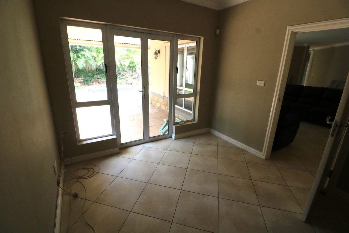 An empty living room featuring neutral tiled flooring and large aluminium sliding doors providing direct access to the outdoor patio area.
