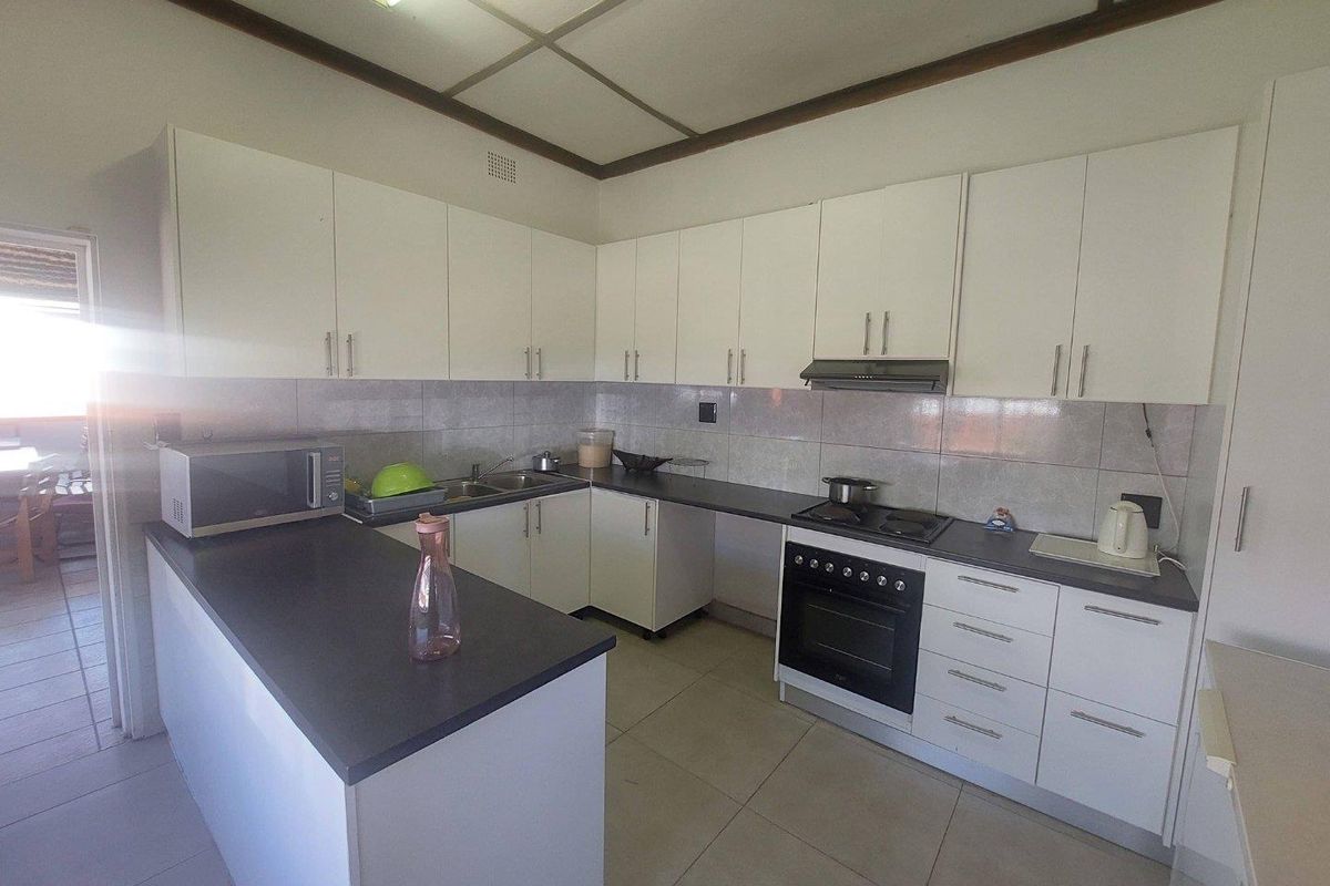 A functional kitchen featuring white cabinetry, dark countertops, a built-in oven with extractor fan, and tiled flooring.