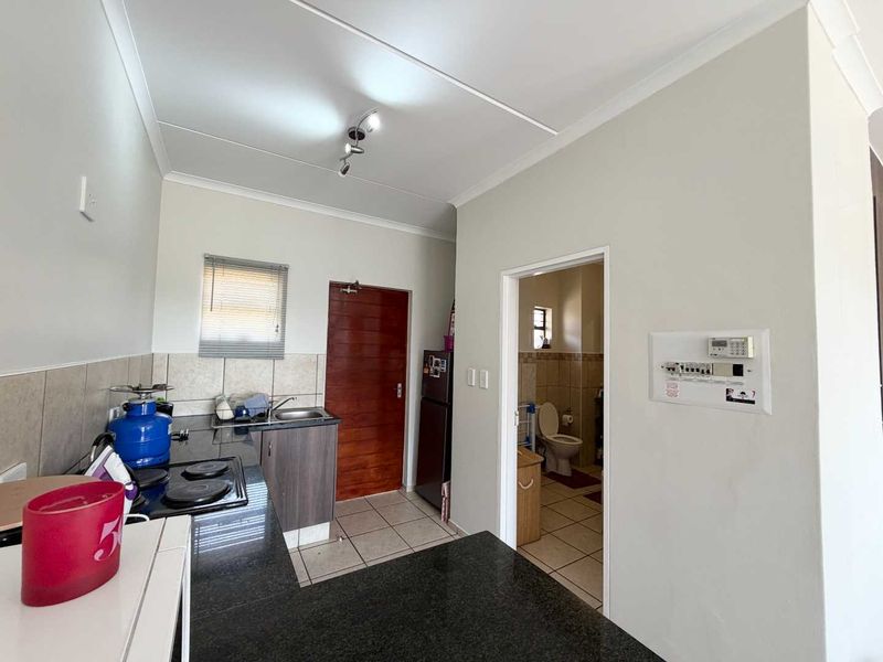 Compact kitchen featuring granite countertops, tiled backsplash, and built-in cabinetry, with direct access to an adjacent bathroom area.