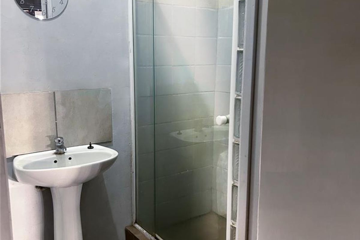 A functional bathroom featuring a pedestal basin and a glass-enclosed shower with glass block accents.