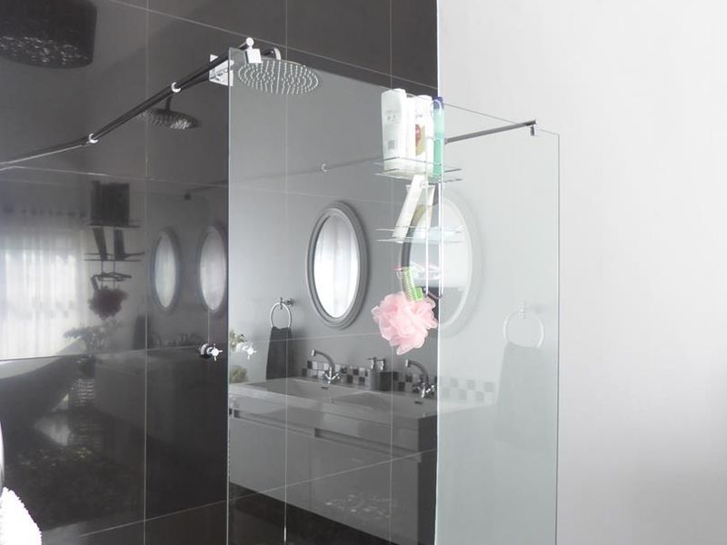 Modern bathroom featuring a spacious walk-in shower with a rain shower head, glass screen, and a sleek double vanity with wall-mounted mirrors.