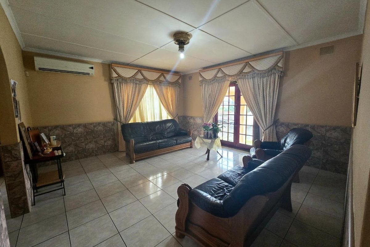 A spacious living room featuring tiled flooring, wall wainscoting, and direct access to the outdoors through double glass doors.