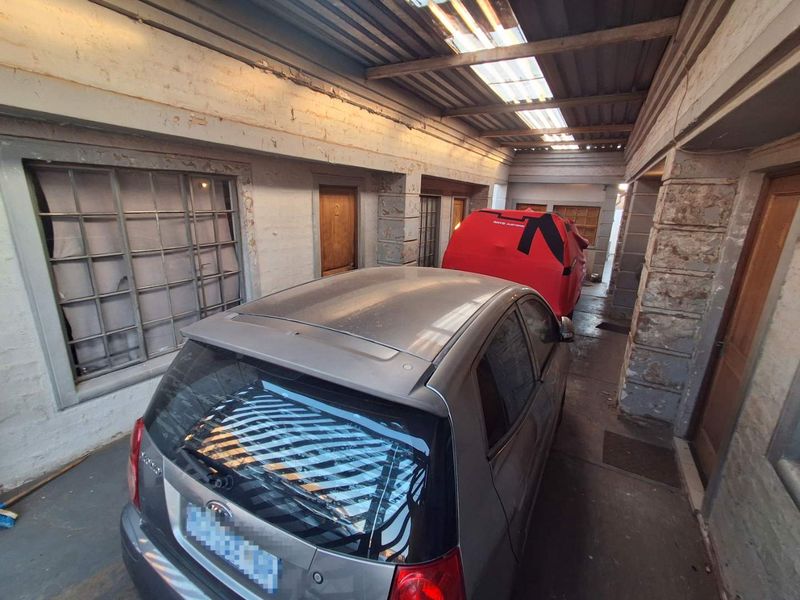 A covered garage area featuring masonry walls, steel-framed windows, and a corrugated metal roof with integrated skylights.