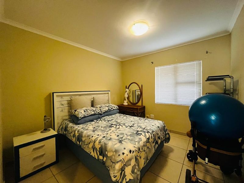 A standard bedroom featuring tiled flooring, neutral wall paint, and venetian blinds, providing a functional and well-lit living space.