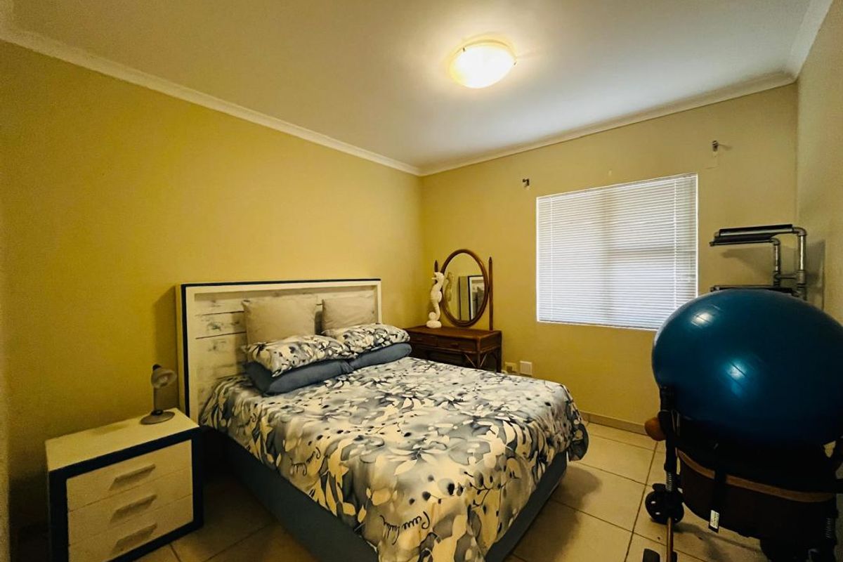 A standard bedroom featuring tiled flooring, neutral wall paint, and venetian blinds, providing a functional and well-lit living space.