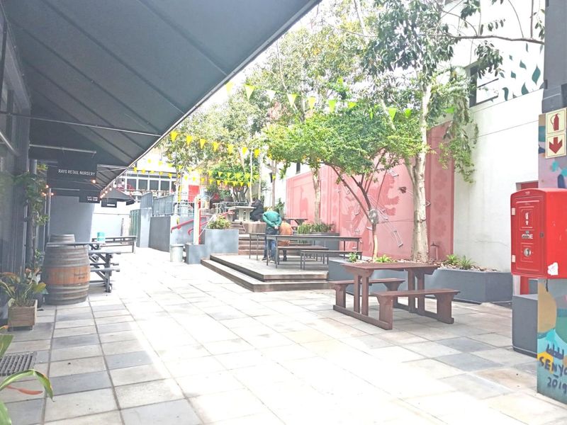 An outdoor courtyard area featuring paved flooring, raised timber decking, and a retractable awning, providing a functional communal space for the office property.