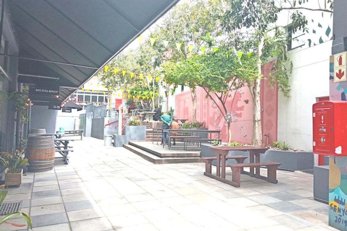 An outdoor courtyard area featuring paved flooring, raised timber decking, and a retractable awning, providing a functional communal space for the office property.