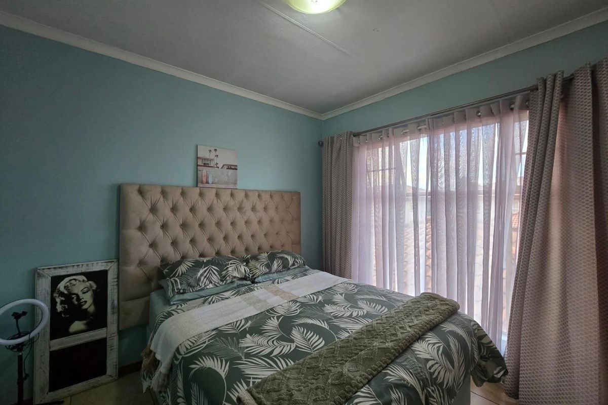 A bedroom featuring tiled flooring, ceiling cornice, and large windows with curtain tracks, providing natural light and a comfortable living space.