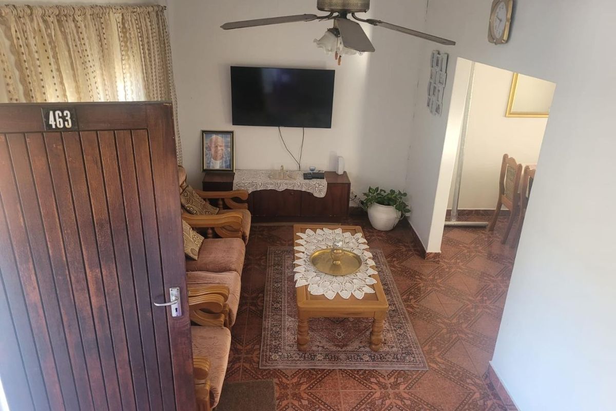 A living room featuring tiled flooring and a ceiling fan, with an open transition to the adjacent dining area.