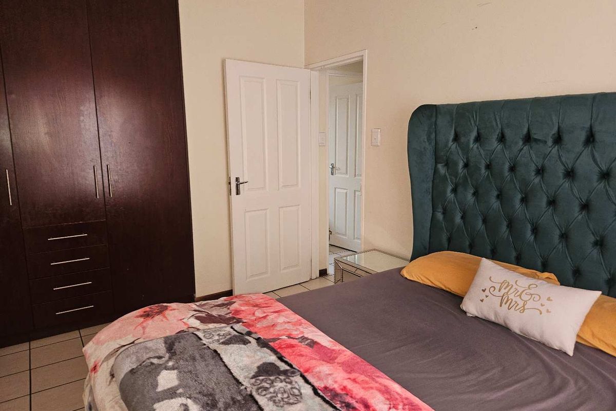 A bedroom featuring built-in dark wood wardrobes and tiled flooring, providing functional storage and a neutral base for interior updates.