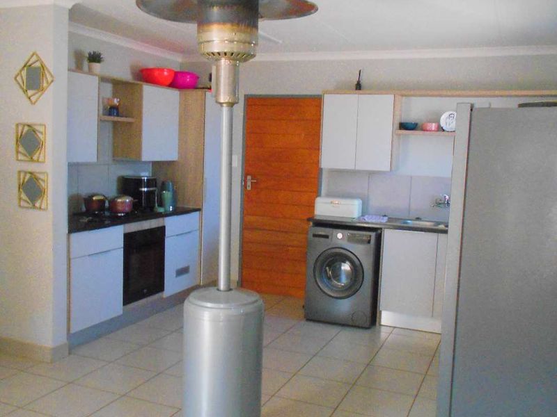 A functional kitchen area featuring built-in cabinetry, an integrated oven, and tiled flooring, providing a practical space for cooking and laundry tasks.