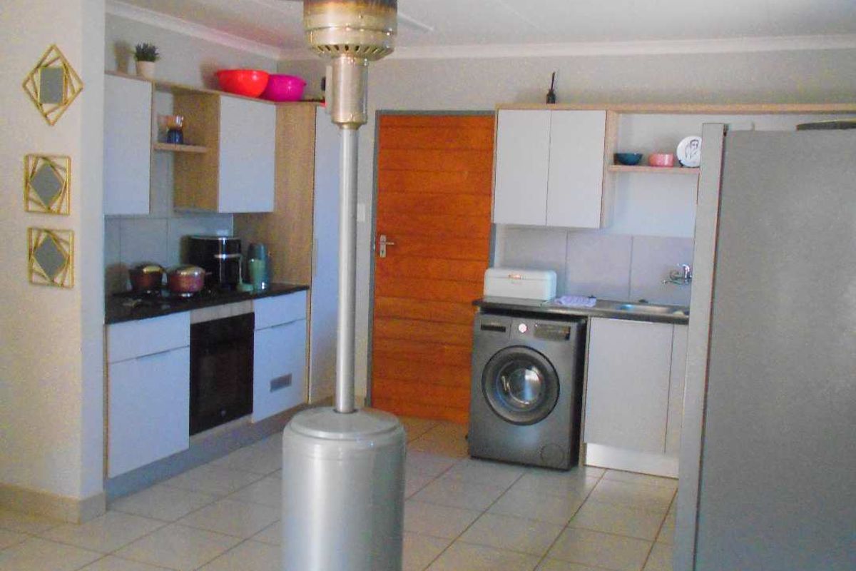 A functional kitchen area featuring built-in cabinetry, an integrated oven, and tiled flooring, providing a practical space for cooking and laundry tasks.