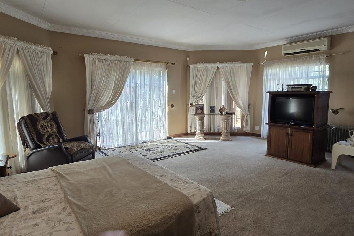Spacious bedroom featuring carpet flooring, air conditioning, and multiple sliding glass doors providing access to the exterior.