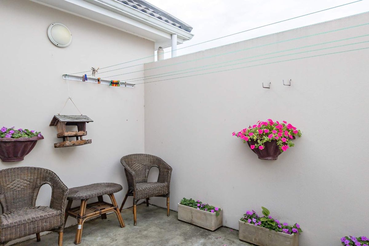 A private courtyard area featuring a wall-mounted retractable clothesline, concrete flooring, and high boundary walls for privacy.