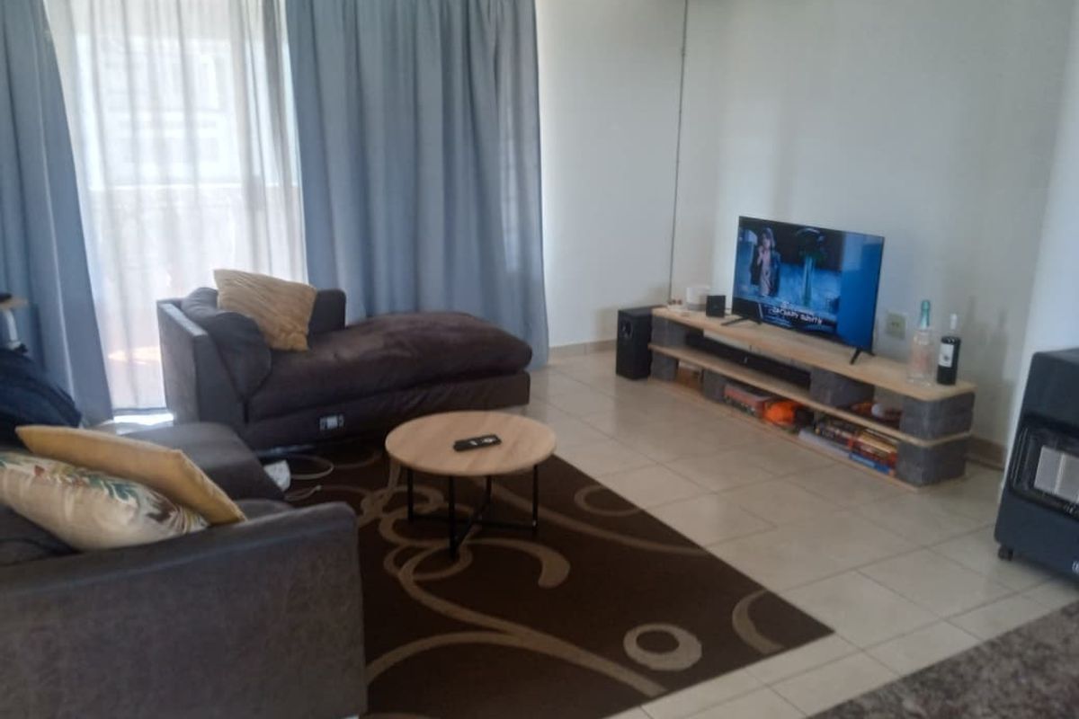 A living room featuring tiled flooring and a sliding glass door leading to an outdoor area, providing natural light to the space.