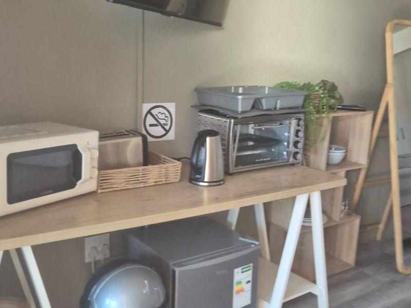 A compact kitchenette area featuring laminate flooring and wall-mounted television, suitable for a small cottage living space.