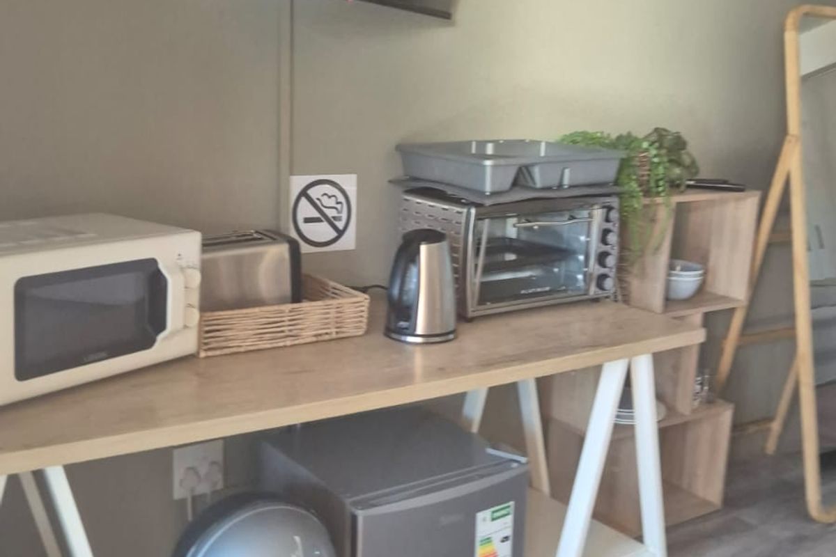 A compact kitchenette area featuring laminate flooring and wall-mounted television, suitable for a small cottage living space.