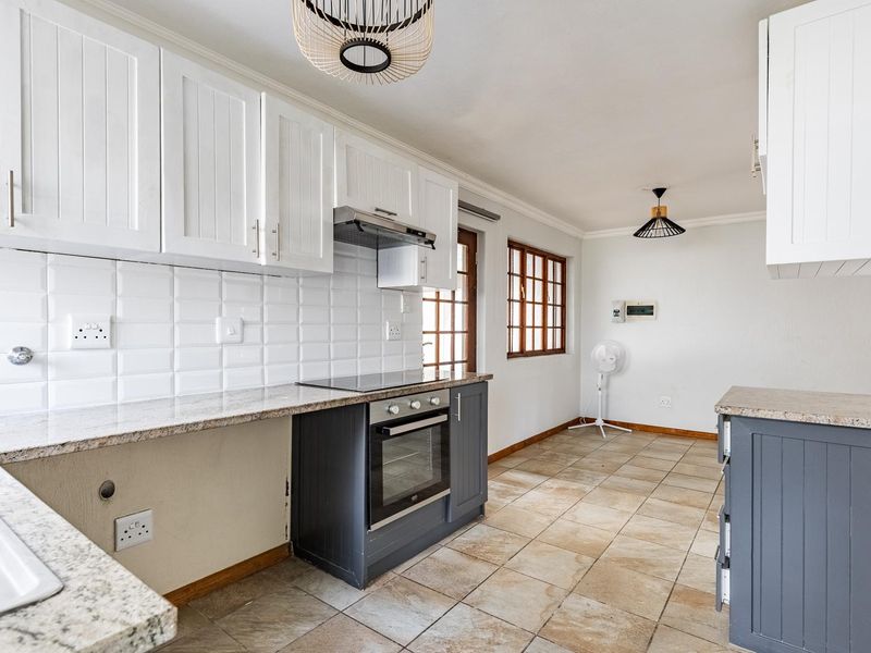 A functional kitchen featuring granite countertops, subway tile backsplash, built-in oven and hob, and ample cabinetry, though requiring minor finishing touches.