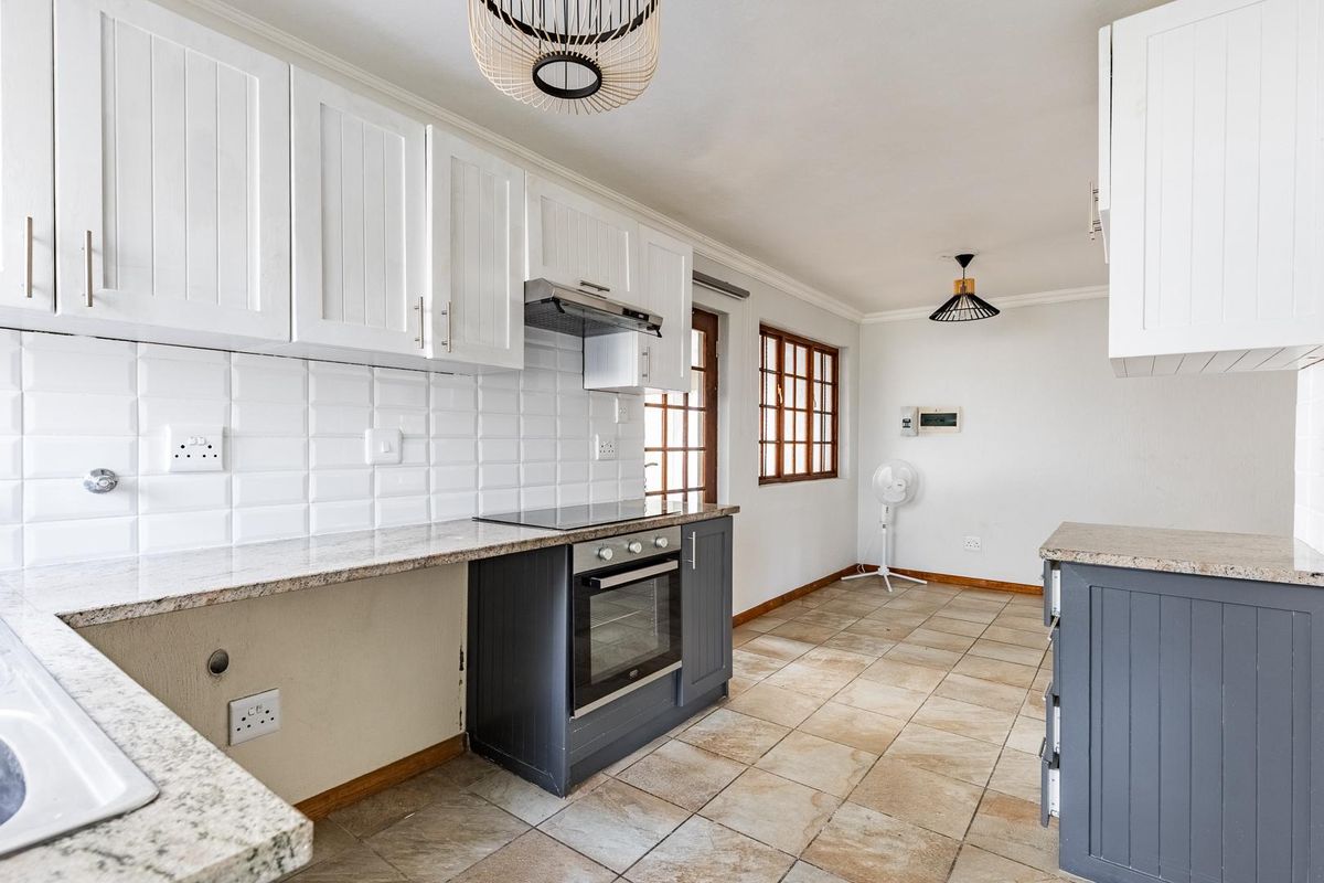 A functional kitchen featuring granite countertops, subway tile backsplash, built-in oven and hob, and ample cabinetry, though requiring minor finishing touches.
