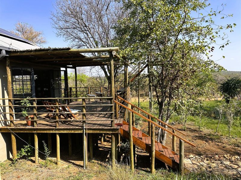 Elevated timber deck and patio area featuring a pergola, wooden balustrades, and a staircase leading down to the garden.