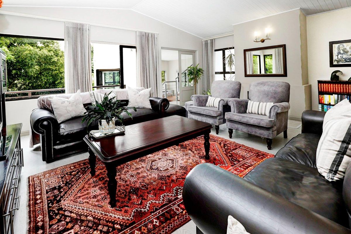 A bright and spacious living room featuring vaulted ceilings, large windows with garden views, and neutral wall finishes.