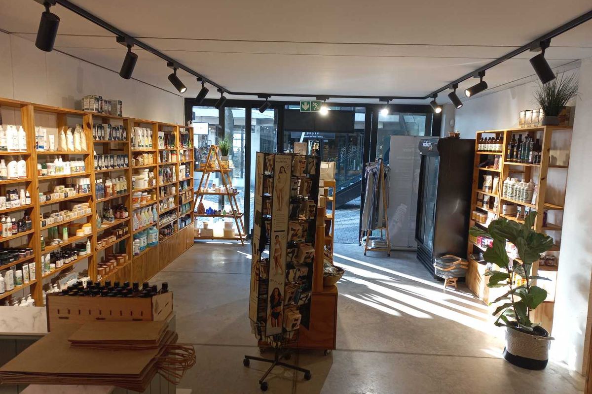 A well-lit retail space featuring polished concrete floors, extensive built-in wooden shelving, and modern track lighting, suitable for various commercial or boutique uses.