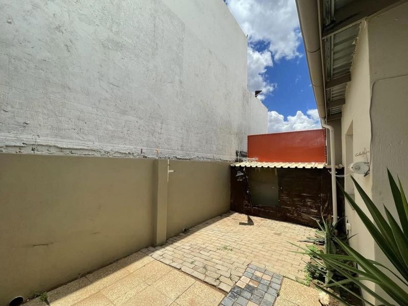 A rear courtyard area featuring paved flooring and boundary walls, offering a private outdoor space with potential for landscaping or improvement.