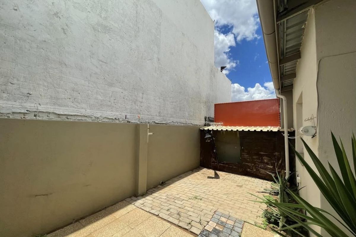 A rear courtyard area featuring paved flooring and boundary walls, offering a private outdoor space with potential for landscaping or improvement.