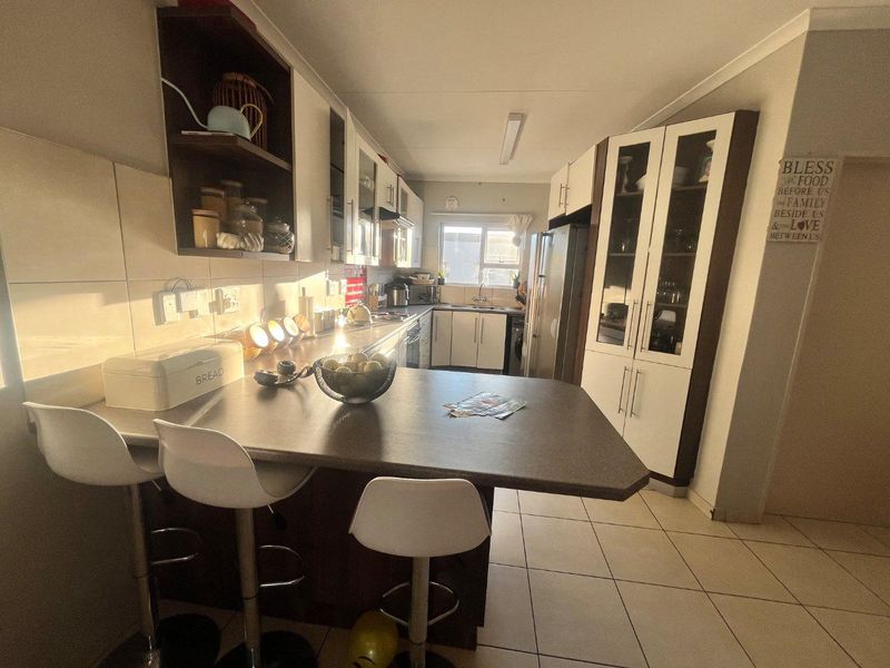 A functional kitchen featuring ample built-in cabinetry, a breakfast bar, tiled backsplash, and tiled flooring, offering a practical layout for daily use.